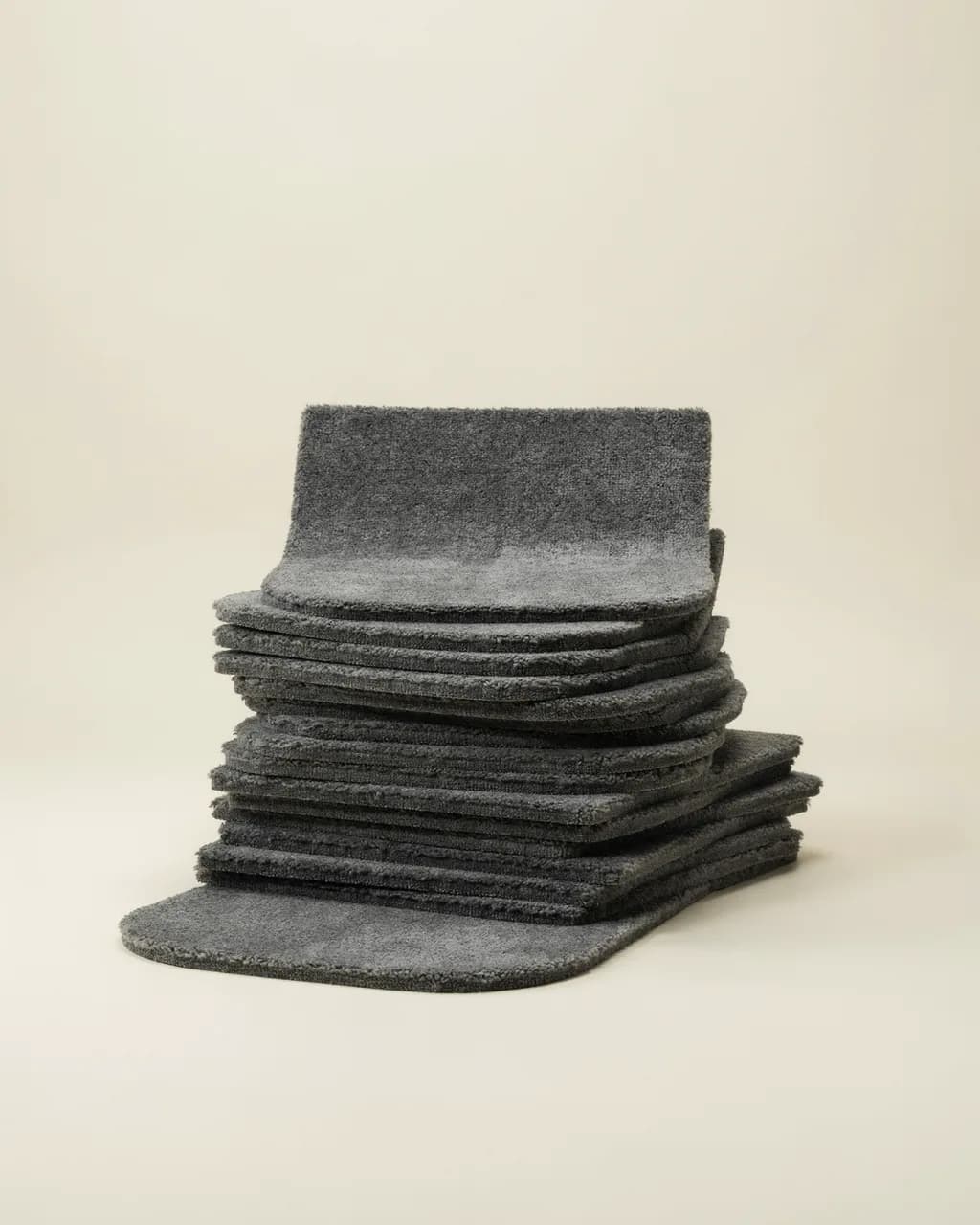 Pile de tapis de marches en moquette gris anthracite au bord avant arrondi, sur fond crème