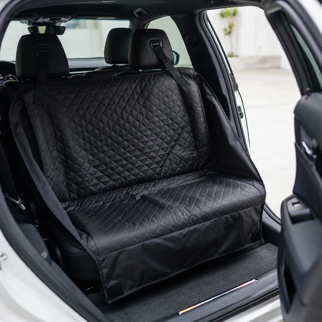 Housse de protection noire matelassée installée sur la banquette arrière d'une voiture, attachée aux appuie-têtes par ses sangles